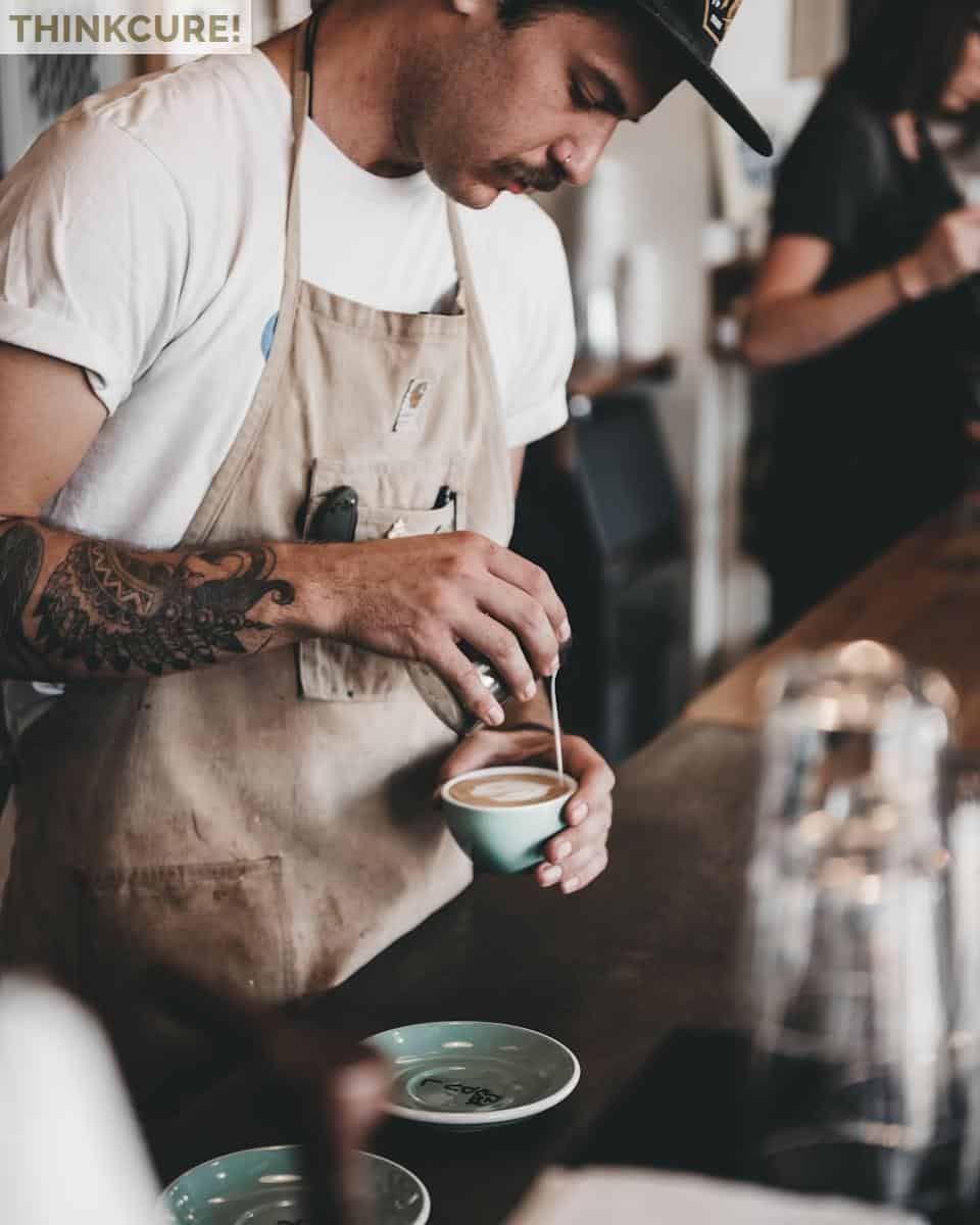 man pouring latte on coffee