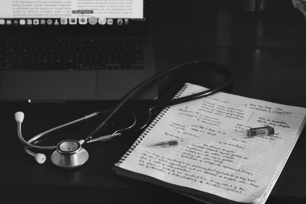 Cuaderno con un estetoscopio junto a un portátil sobre una mesa